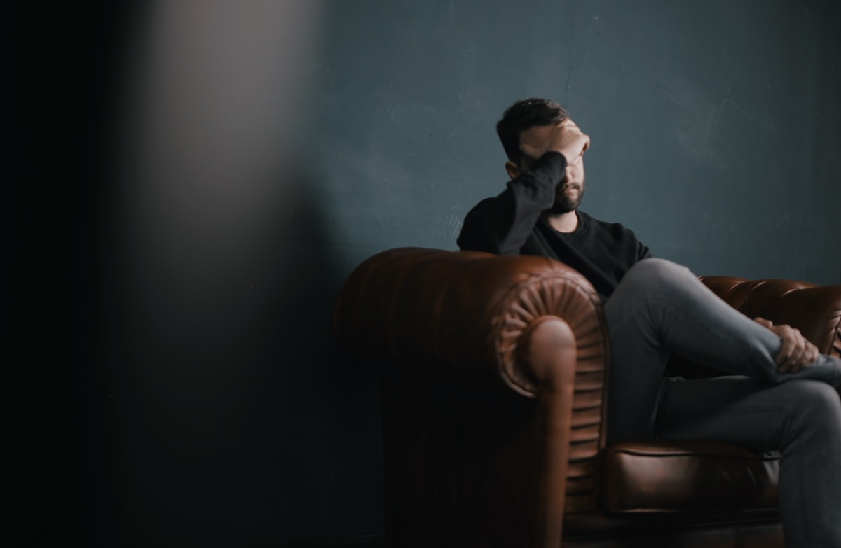 Person sitting alone, head in hand — representing anxiety and nervous system overwhelm